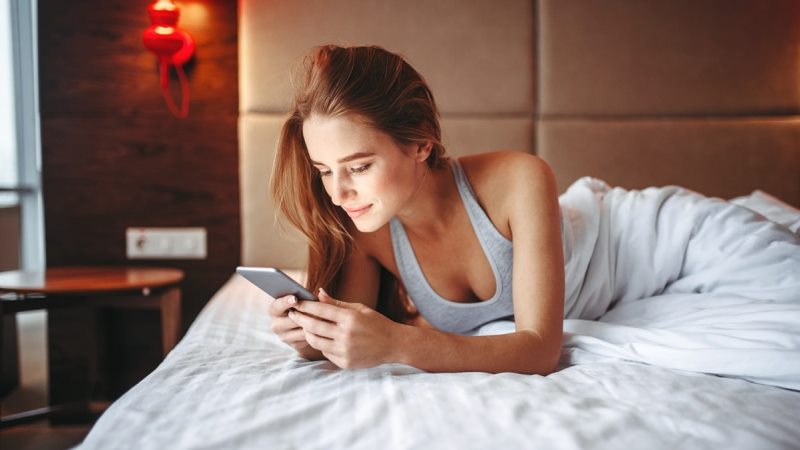 Attractive-woman-lies-in-bed-and-using-phone